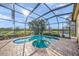 Beautiful pool and spa surrounded by a screened lanai and lush landscaping with views of the water at 7108 Callander Cv, Lakewood Ranch, FL 34202