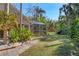 Landscaped backyard with lush green grass, tropical plants, and screened-in porch provides a serene outdoor space at 7821 Geneva Ln # 11, Sarasota, FL 34243