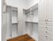 Bright walk-in closet with custom white shelving and drawers and wood floor at 8016 Bowspirit Way, Lakewood Ranch, FL 34202