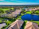 Aerial view showcases homes with tile roofs nestled near a serene lake and lush green golf course at 8310 Tartan Fields Cir, Lakewood Ranch, FL 34202