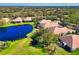Aerial view of luxury homes near a large pond with manicured green space on a sunny day with lush, wooded surroundings at 8310 Tartan Fields Cir, Lakewood Ranch, FL 34202