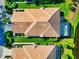 Aerial view of a well-maintained home showcasing its tile roof, lush landscaping, and screened-in pool area at 8310 Tartan Fields Cir, Lakewood Ranch, FL 34202