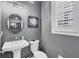 Cozy bathroom featuring a pedestal sink, round mirror and a floral-themed wall decor at 10600 Lemon Creek Loop # 102, Englewood, FL 34224