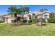 Well-maintained house exterior with a green lawn, palm trees, and manicured landscaping on a sunny day at 11031 Hyacinth Pl, Lakewood Ranch, FL 34202