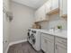Bright laundry room features modern washer and dryer, white cabinetry, and wood-look tile flooring at 12423 Blue Hill Trl, Lakewood Ranch, FL 34211
