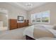 Bright primary bedroom with hardwood furniture, neutral decor, and large window at 12423 Blue Hill Trl, Lakewood Ranch, FL 34211