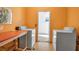 Community laundry room featuring two washing machines, one dryer, and an orange colored wall at 3860 Ironwood Ln # 503G, Bradenton, FL 34209