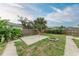 A fenced backyard featuring a small palm tree, concrete patio, and stone fire pit at 402 Ravenna N St, Nokomis, FL 34275