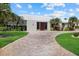 Single-story home with a paver driveway leading to a wooden entry, surrounded by mature landscaping at 432 Partridge Cir, Sarasota, FL 34236