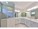 Bright bathroom featuring white cabinetry, dual sinks, large mirrors, and a glass-enclosed tiled shower at 4516 Renwick Dr, Parrish, FL 34219