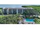 A beautiful aerial view of a white condo community, including a swimming pool surrounded by lush tropical greenery at 4600 Gulf Of Mexico Dr # 202, Longboat Key, FL 34228