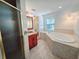 A bathroom featuring tile floors, a large tub, shower, a window, and a red vanity at 611 19Th W Ave, Palmetto, FL 34221