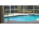 Relaxing screened-in pool with a spill-over spa and clear blue water, set against a lush green backdrop at 629 Sawgrass Bridge Rd, Venice, FL 34292
