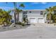 Beautiful two-story home featuring a two-car garage, lush landscaping, and a charming circular window detail at 9 Palm Harbor Dr, Holmes Beach, FL 34217