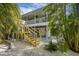 Two-story home featuring a spacious balcony, wooden stairs, and a charming backyard with lush greenery at 9 Palm Harbor Dr, Holmes Beach, FL 34217