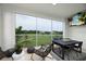 A modern screened-in dining area featuring a dark wood table, wicker chairs, and a relaxing view of lush greenery at 9998 Key Haven Rd, Seminole, FL 33777