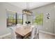 Bright dining room with a wooden table, white chairs, a stylish light fixture, and large windows at 2720 Butterfly Jasmine Trl, Sarasota, FL 34240
