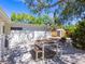 Outdoor patio features a dining table, white stucco wall, storage shed, and mature landscaping at 3629 Almeria Ave, Sarasota, FL 34239