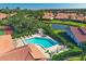 Aerial view of a community pool, tennis courts, and surrounding homes with red tile roofs at 3825 Wilshire Cir # 1, Sarasota, FL 34238