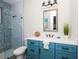 Modern bathroom with a blue vanity, quartz countertop, framed mirror and mosaic tiled shower with glass door at 401 20Th Pl, Bradenton Beach, FL 34217