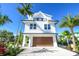Charming white two-story home with a brown garage door and a balcony surrounded by lush tropical landscaping at 401 20Th Pl, Bradenton Beach, FL 34217