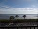 Scenic ocean view with three palm trees in the foreground, lush greenery, and a clear blue sky at 4555 Bay Club Dr # 22, Bradenton, FL 34210