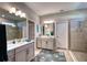 Bright bathroom with a double vanity, tiled walk-in shower, and a seashell rug at 4706 Roycroft Ter, Parrish, FL 34219