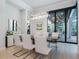 Elegant dining room with modern chandelier and sleek table, leading to an outdoor living space through sliding glass doors at 4940 Peaceable Way, Sarasota, FL 34242