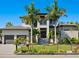 Stunning two-story modern home with manicured lawn, palm trees, metal fence, and a two-car garage at 4940 Peaceable Way, Sarasota, FL 34242