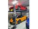 Spacious garage featuring a vehicle lift with an orange McLaren and red Ferrari parked in a multi-vehicle garage at 4940 Peaceable Way, Sarasota, FL 34242