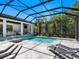 Stunning screened-in pool area with modern lounge chairs, spa, outdoor kitchen and lush landscaping at 4940 Peaceable Way, Sarasota, FL 34242