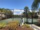 This tennis court has trees and vegetation surrounding it, as well as a blue sky above at 5701 Bentgrass Dr # 18-203, Sarasota, FL 34235
