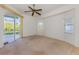 Bright bedroom features neutral carpet, ceiling fan, and sliding glass doors to screened patio at 5872 Mckinley Rd, Venice, FL 34293