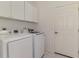 Well-lit laundry room features a washer, dryer, white cabinets, and a tiled floor at 5872 Mckinley Rd, Venice, FL 34293