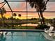 Tranquil pool area at sunset with lounge chairs, palm trees, and a view of the pond with golf course beyond at 6 Bunker Cir, Rotonda West, FL 33947