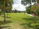 Lush backyard with a manicured lawn, mature trees, and a walking path at 6042 Red Maple Rd # 1001, Bradenton, FL 34210