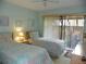 Cozy bedroom with two twin beds, light blue walls, and sliding glass doors to outside at 6042 Red Maple Rd # 1001, Bradenton, FL 34210