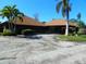 Low-rise building with unique roof and circular driveway, landscaped with palm trees and bushes at 6042 Red Maple Rd # 1001, Bradenton, FL 34210