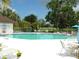 Community swimming pool with lounge chairs and tables, surrounded by tropical trees and landscaping at 6042 Red Maple Rd # 1001, Bradenton, FL 34210