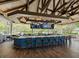 Open-air bar with a wood beam ceiling, multiple TVs, a well-stocked bar, and views of the surrounding landscape at 6316 Walton Heath Pl, University Park, FL 34201