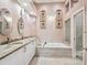 A luxurious bathroom featuring a soaking tub, glass shower, and a double vanity with granite countertops at 6316 Walton Heath Pl, University Park, FL 34201