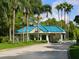 A landscaped community entrance with a blue tile roof and the American flag waving above lush green trees at 6316 Walton Heath Pl, University Park, FL 34201