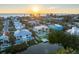 Aerial sunset view of a coastal neighborhood featuring a modern waterfront home with a private dock at 7003 Holmes Blvd, Holmes Beach, FL 34217