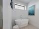This bathroom features a standalone tub, tiled floors, modern fixtures, and a small window at 7003 Holmes Blvd, Holmes Beach, FL 34217