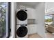 Modern laundry room with stacked washer and dryer and white cabinets next to the living area at 7003 Holmes Blvd, Holmes Beach, FL 34217