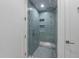 Tiled walk-in shower with glass door, featuring multiple shower heads and built-in shelving at 7003 Holmes Blvd, Holmes Beach, FL 34217