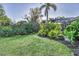 Manicured backyard features a verdant lawn and lush landscaping, with the pool enclosure visible in the distance at 7665 Portstewart Dr, Lakewood Ranch, FL 34202