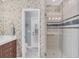 Bathroom with a glass walk-in shower, patterned wallpaper, and a wooden vanity at 7665 Portstewart Dr, Lakewood Ranch, FL 34202