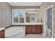 Bathroom with a soaking tub, patterned wallpaper, and wooden vanity with storage at 7665 Portstewart Dr, Lakewood Ranch, FL 34202