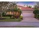 Charming single-story home with a red tile roof, lush landscaping, and a brick-paved driveway leading to an attached garage at 7665 Portstewart Dr, Lakewood Ranch, FL 34202